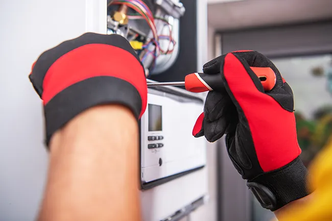 An HVAC technician working on a gas furnace.